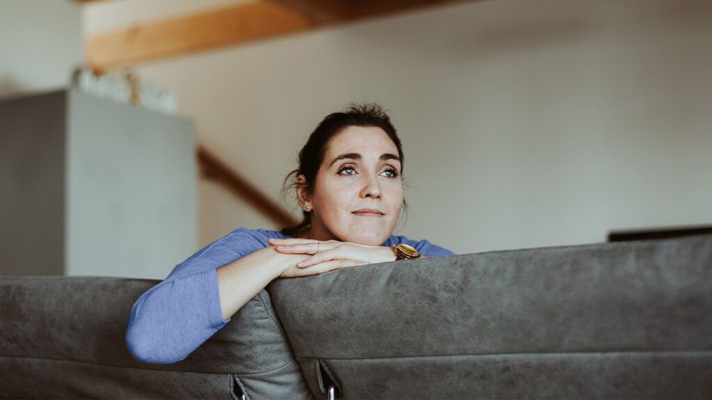 A pensive woman sits on a sofa